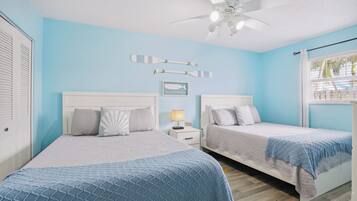 A bedroom with two beds, a ceiling fan, and a window with blinds.