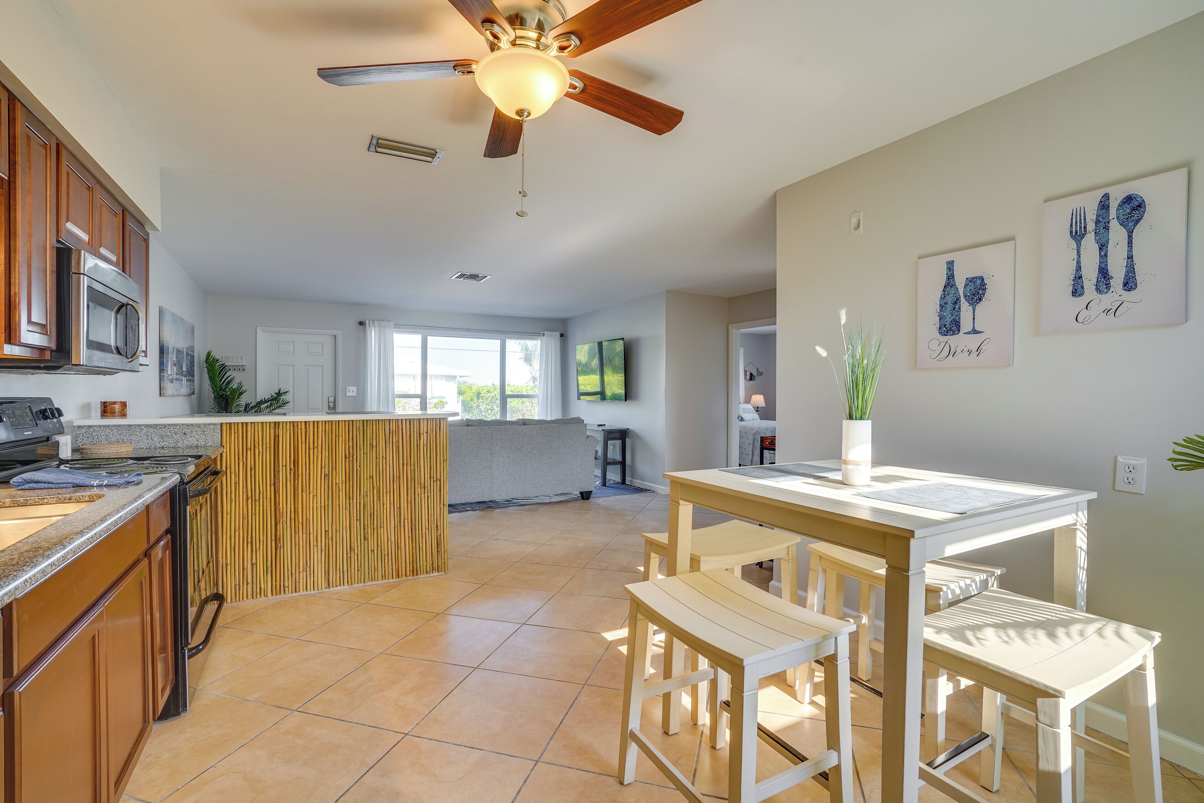 A spacious kitchen with a central island, wooden cabinets, and a ceiling fan.