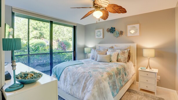 A bedroom with a bed, a desk with a lamp, a nightstand, and a ceiling fan. - Bonita Springs Vacation Rental w/ Community Pool! (Bonita Springs)