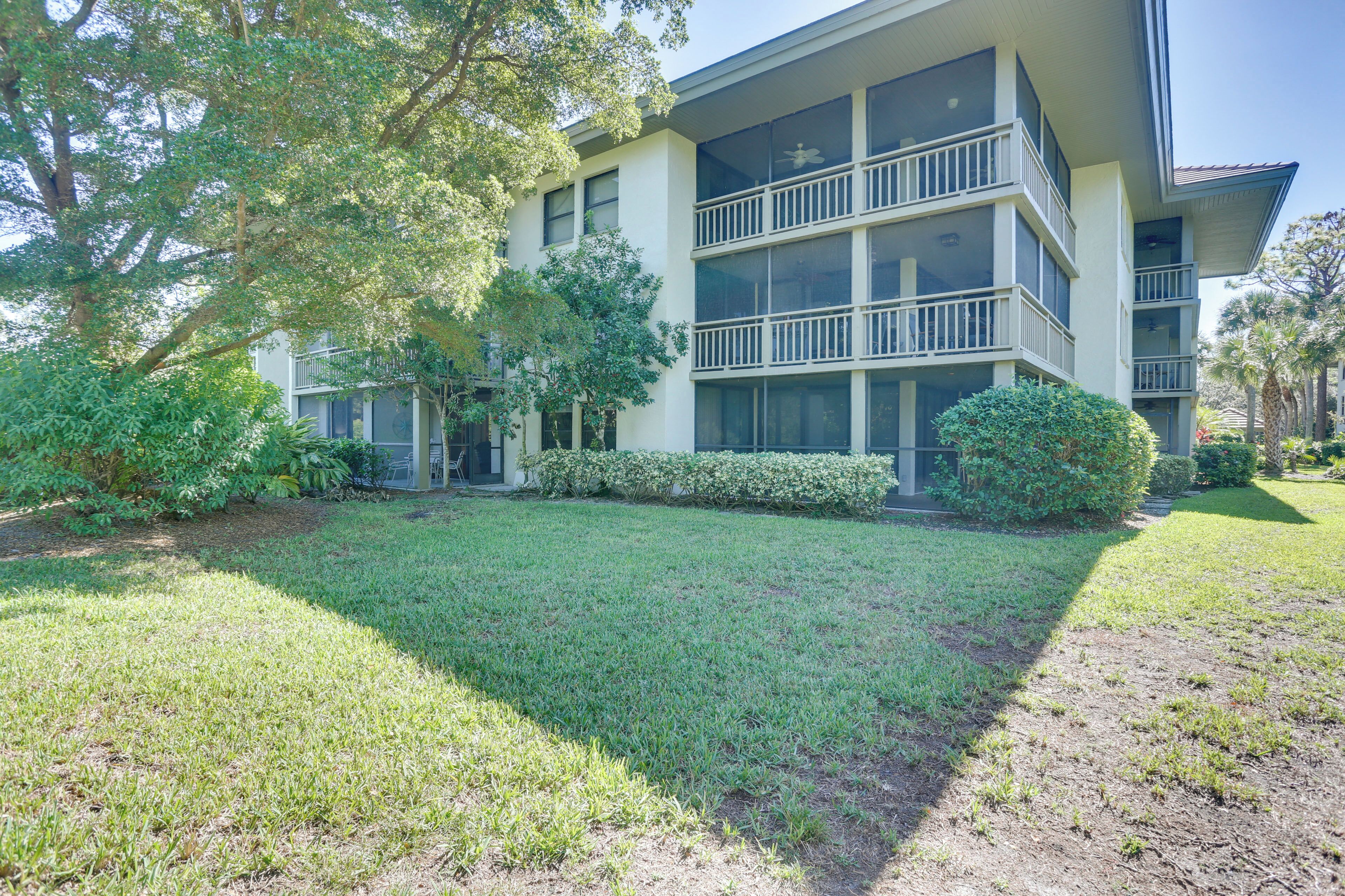 A multi-story building with balconies, surrounded by well-maintained lawns and trees.