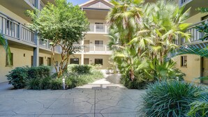 A courtyard with a central pathway surrounded by lush greenery and a multi-story building with balconies. - Bonita Springs Vacation Rental w/ Community Pool! (Bonita Springs)