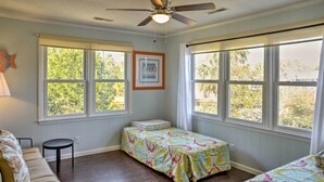 A room with two beds, a ceiling fan, and large windows. - Canalfront Surfside Beach Home - Walk to Beach! (Surfside Beach)