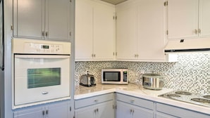 A kitchen with white cabinets, a microwave, a toaster, and a stove. - Canalfront Surfside Beach Home - Walk to Beach! (Surfside Beach)