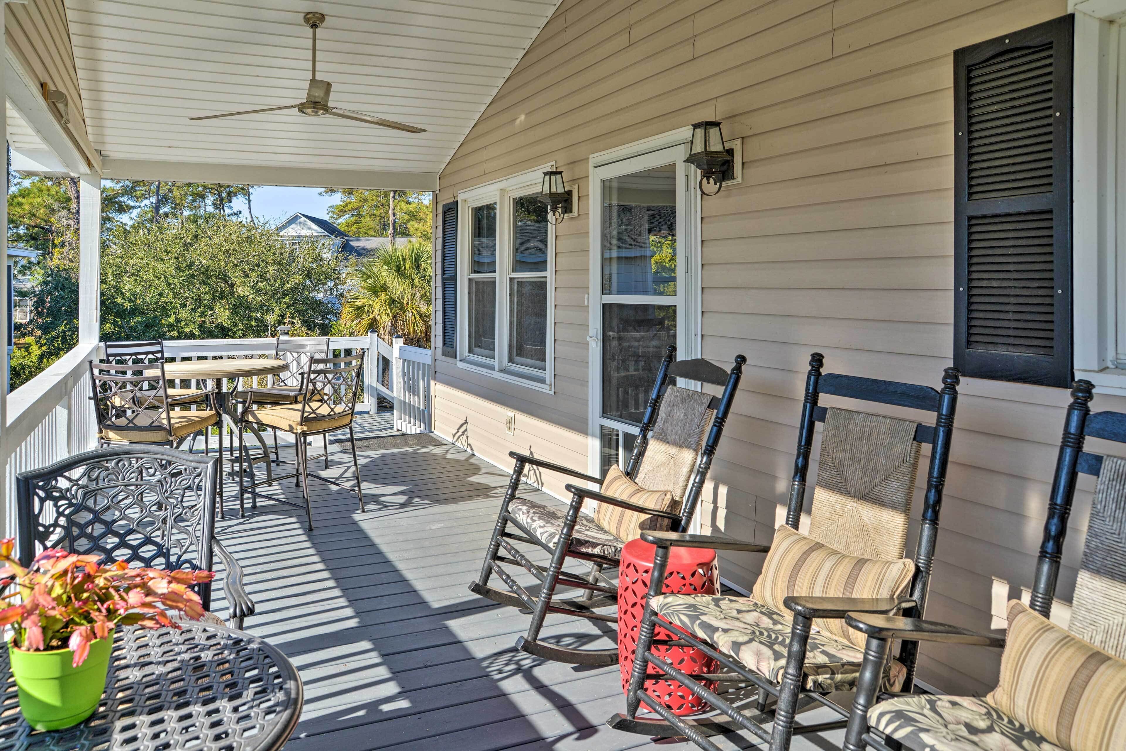 A covered porch with outdoor furniture, including chairs and a table, and a ceiling fan.