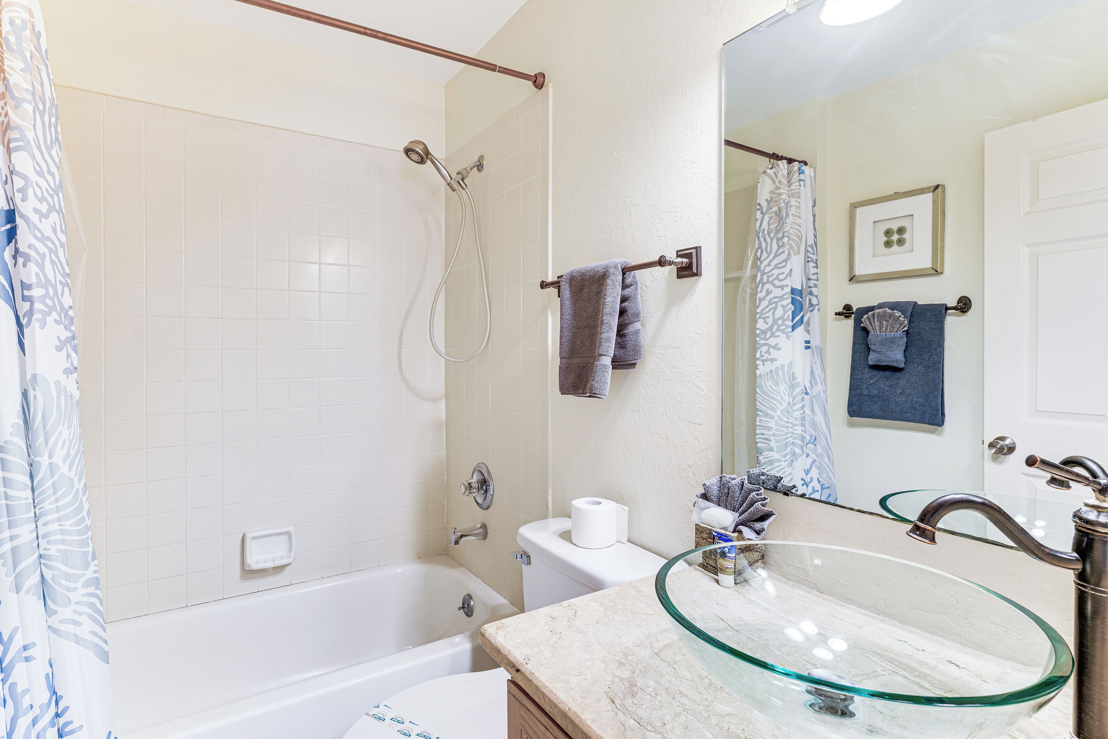 Une salle de bain avec un lavabo en verre, une baignoire, une douche et des toilettes.