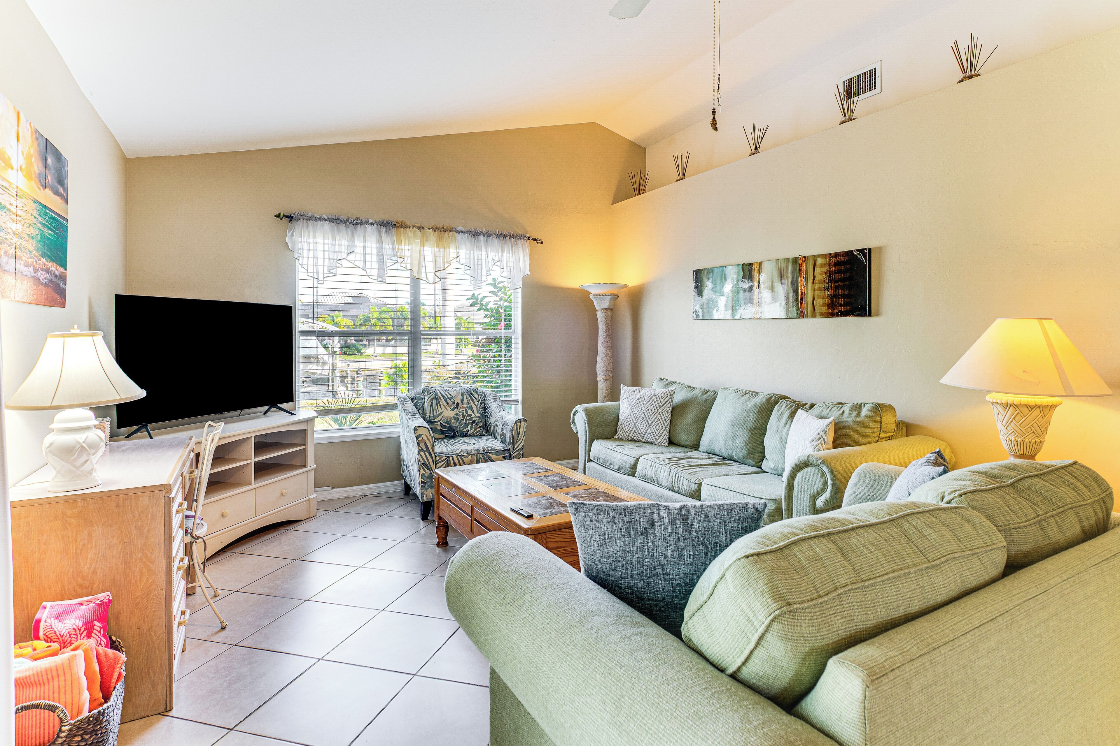 A living room with a sofa, a coffee table, a TV, and a window with curtains.