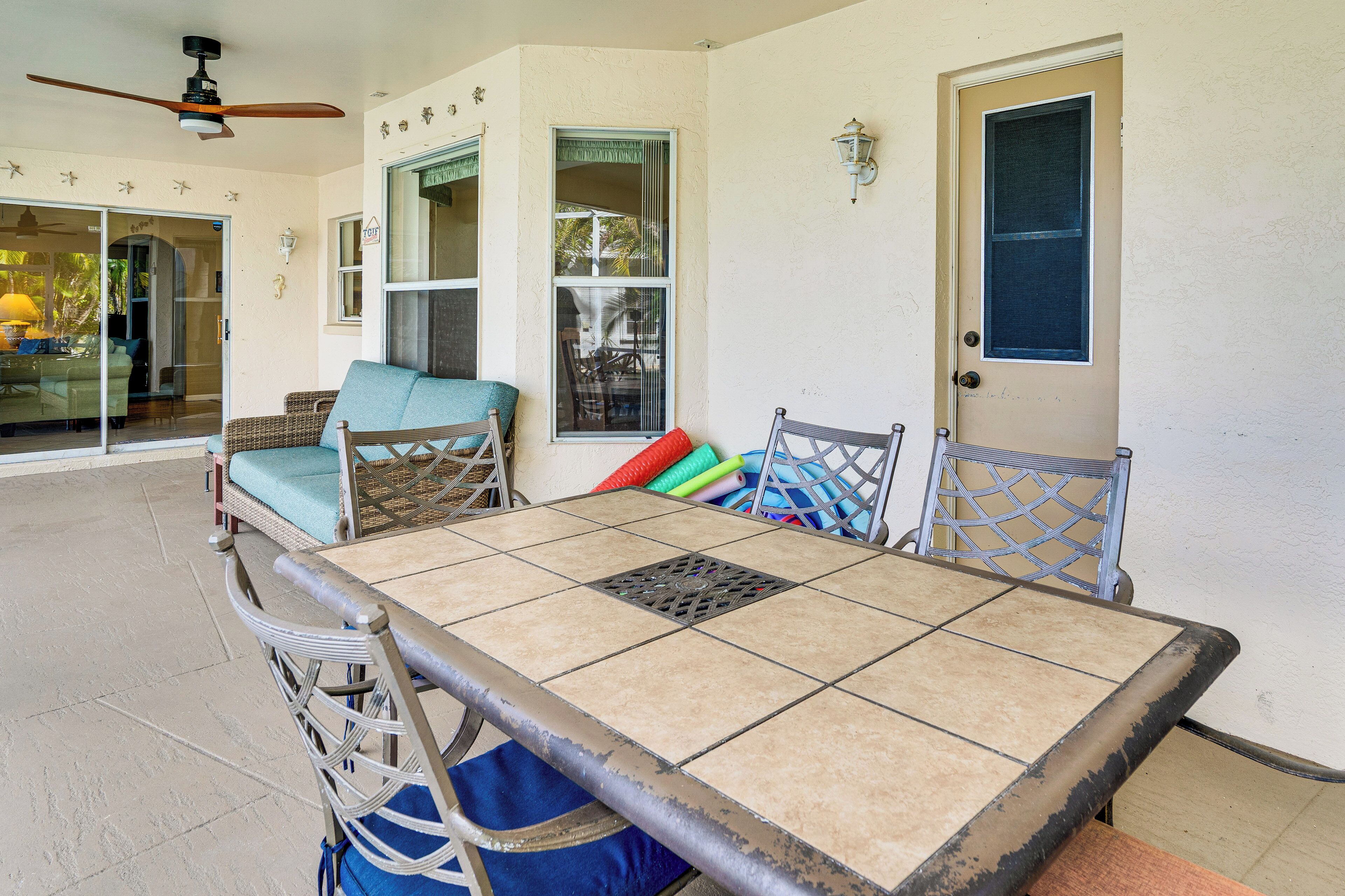 A dining area with a table and chairs, a ceiling fan, and a door.