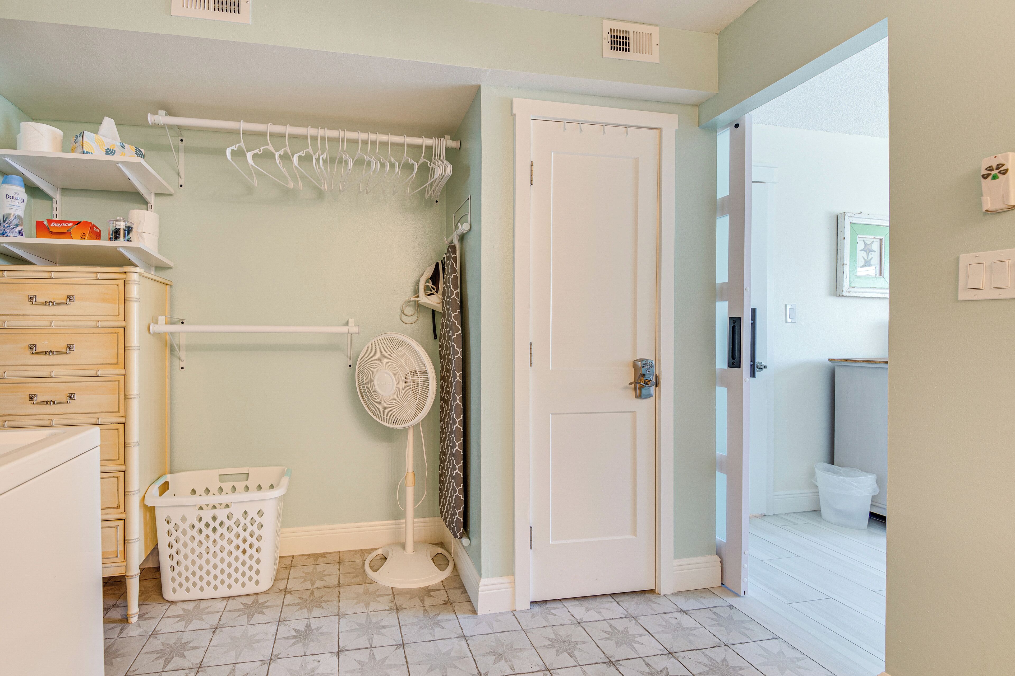 A laundry room with a washing machine, a dryer, a fan, and a laundry basket.