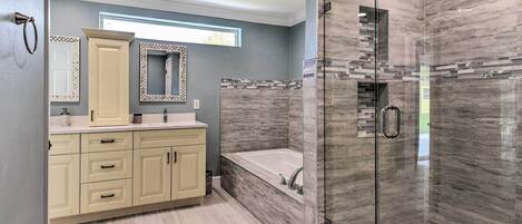 A modern bathroom with a glass-enclosed shower, a freestanding bathtub, and a vanity with a mirror.