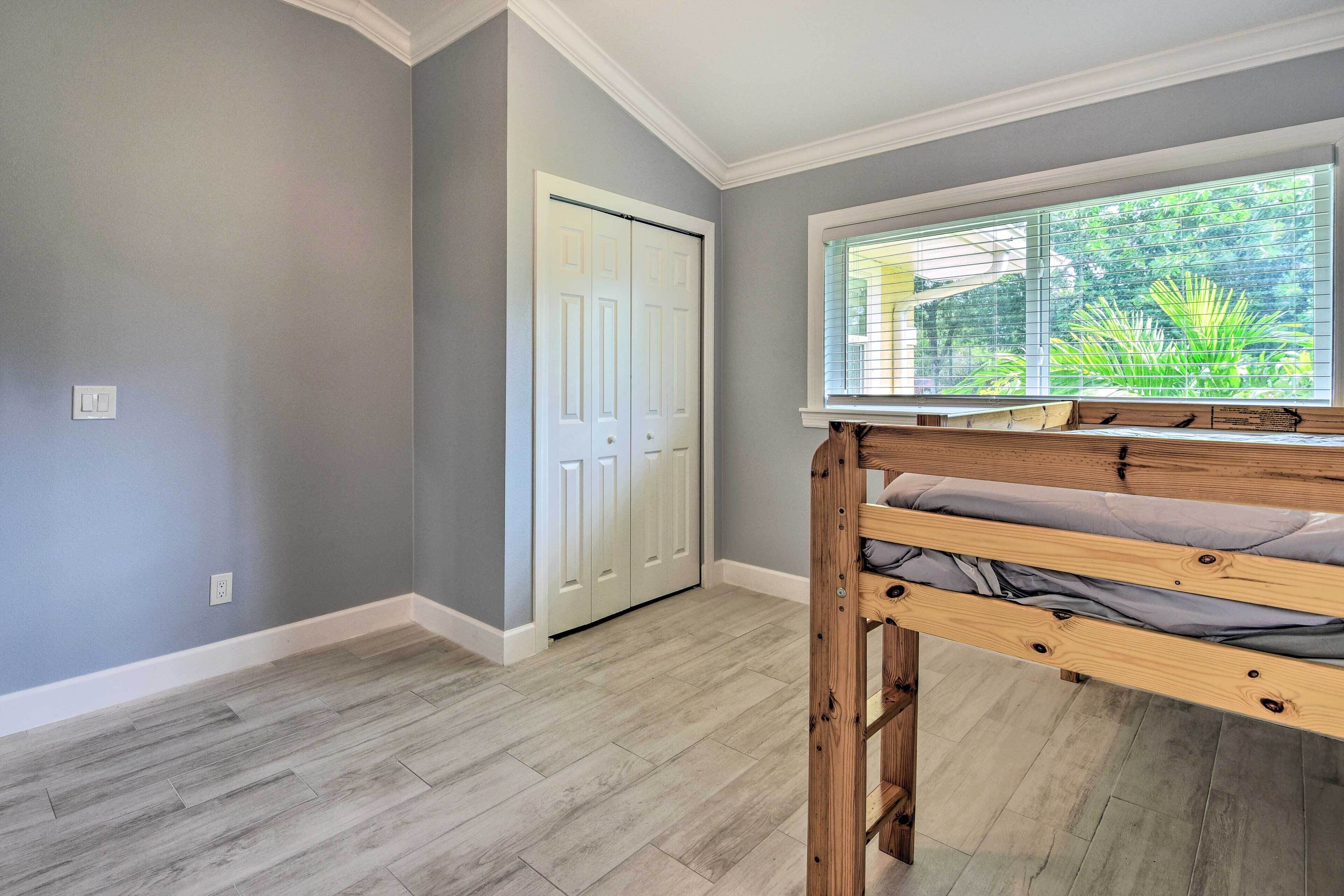 A room with a bunk bed, grey walls, a white door, and a window with blinds.