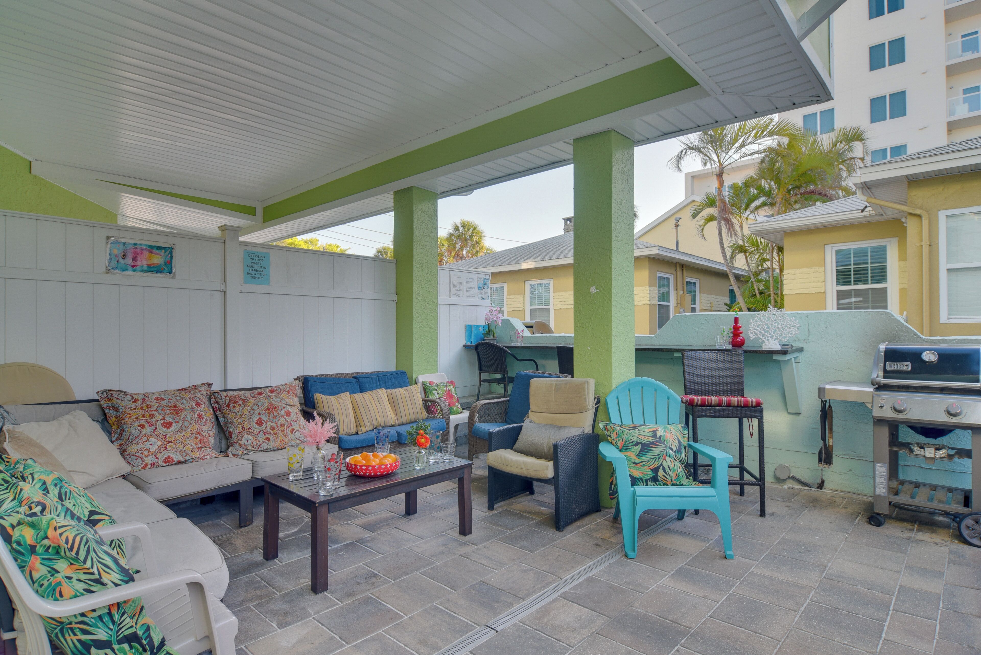 An outdoor patio with a covered seating area, a grill, and a dining table.