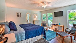 A bedroom with a bed, a desk, a chair, a TV, and large windows. - Brandon Vacation Rental Home w/ Spacious Yard (Brandon)