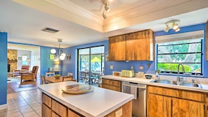 A modern kitchen with wooden cabinets, a white countertop, and a large window with a view of greenery. - Brandon Vacation Rental Home w/ Spacious Yard (Brandon)