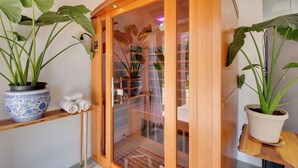 Ein Holzkabinent mit Glastüren, darin eine Topfpflanze und ein gefaltetes Handtuch.