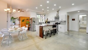 Eine moderne Küche mit Kochinsel, weißen Schränken und Deckenventilator.
