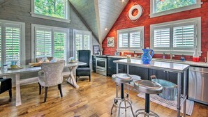 A kitchen with wooden walls, a dining area with a table and chairs, and a bar area with stools.
