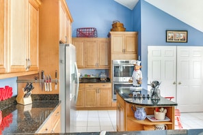 A kitchen with wooden cabinets, a refrigerator, a microwave, and a stove.