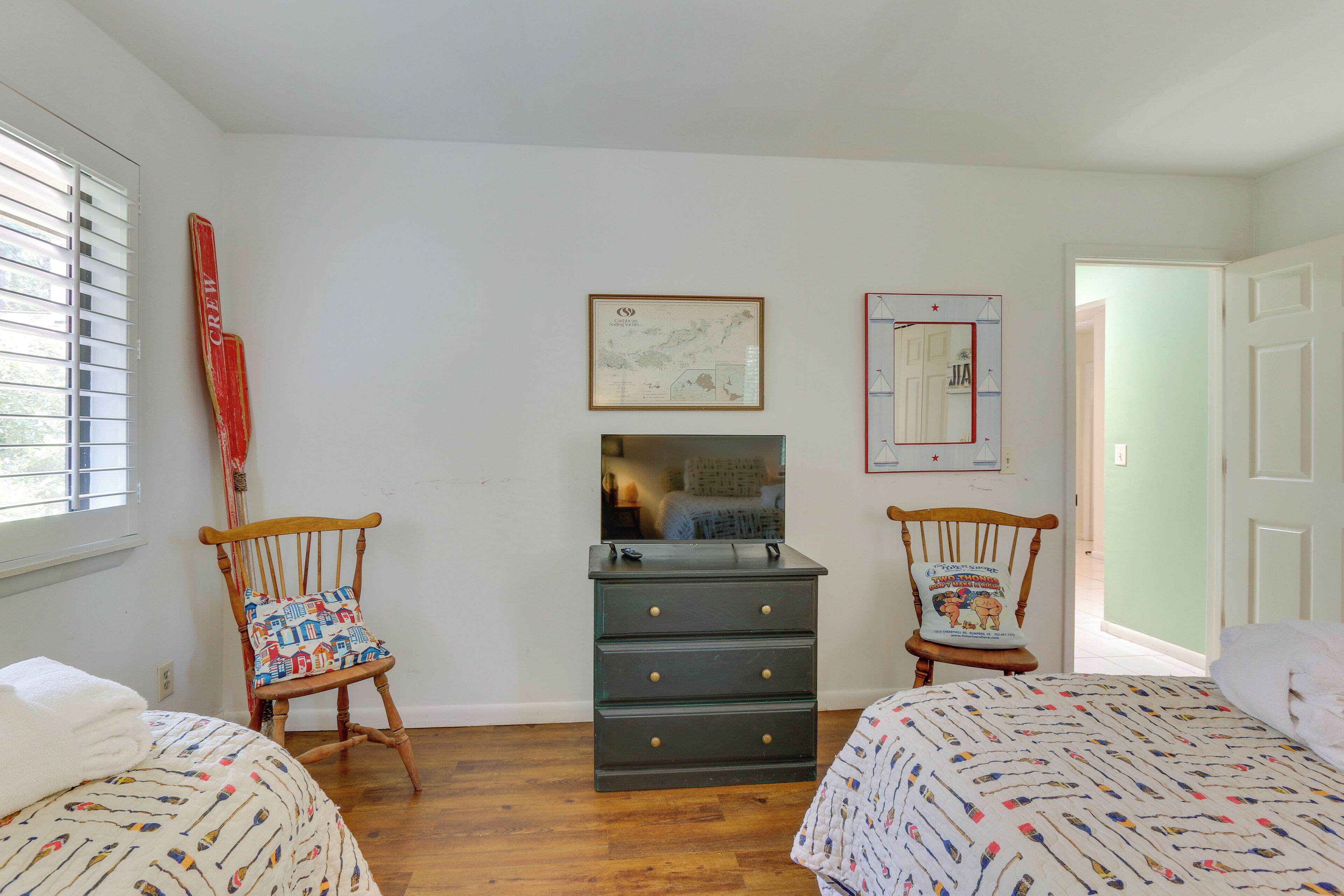 A bedroom with two single beds, a dresser, a mirror, and a window with blinds.