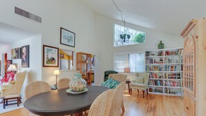 A dining area with wicker chairs, a round table, and a bookshelf filled with books. - 2 Mi to Beach: Hilton Head Home w/ Furnished Deck (Hilton Head Island)
