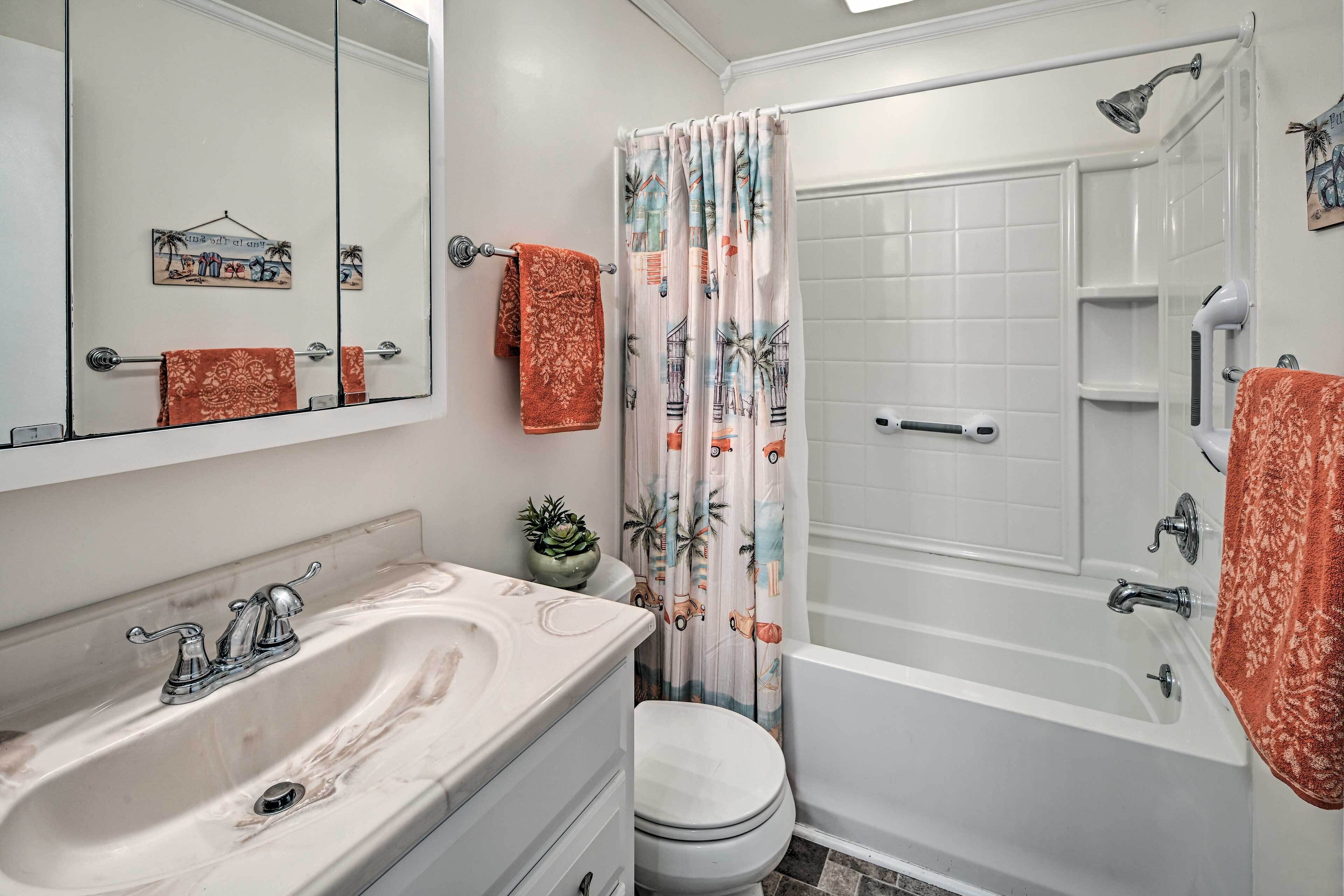 A bathroom with a bathtub, a sink, a toilet, a mirror, and a shower curtain.