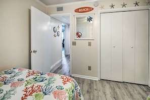 A bedroom with a bed, a wardrobe, a hallway, and a door leading to another room. - Myrtle Beach Condo w/ On-site Pool & Beach Access (Myrtle Beach)