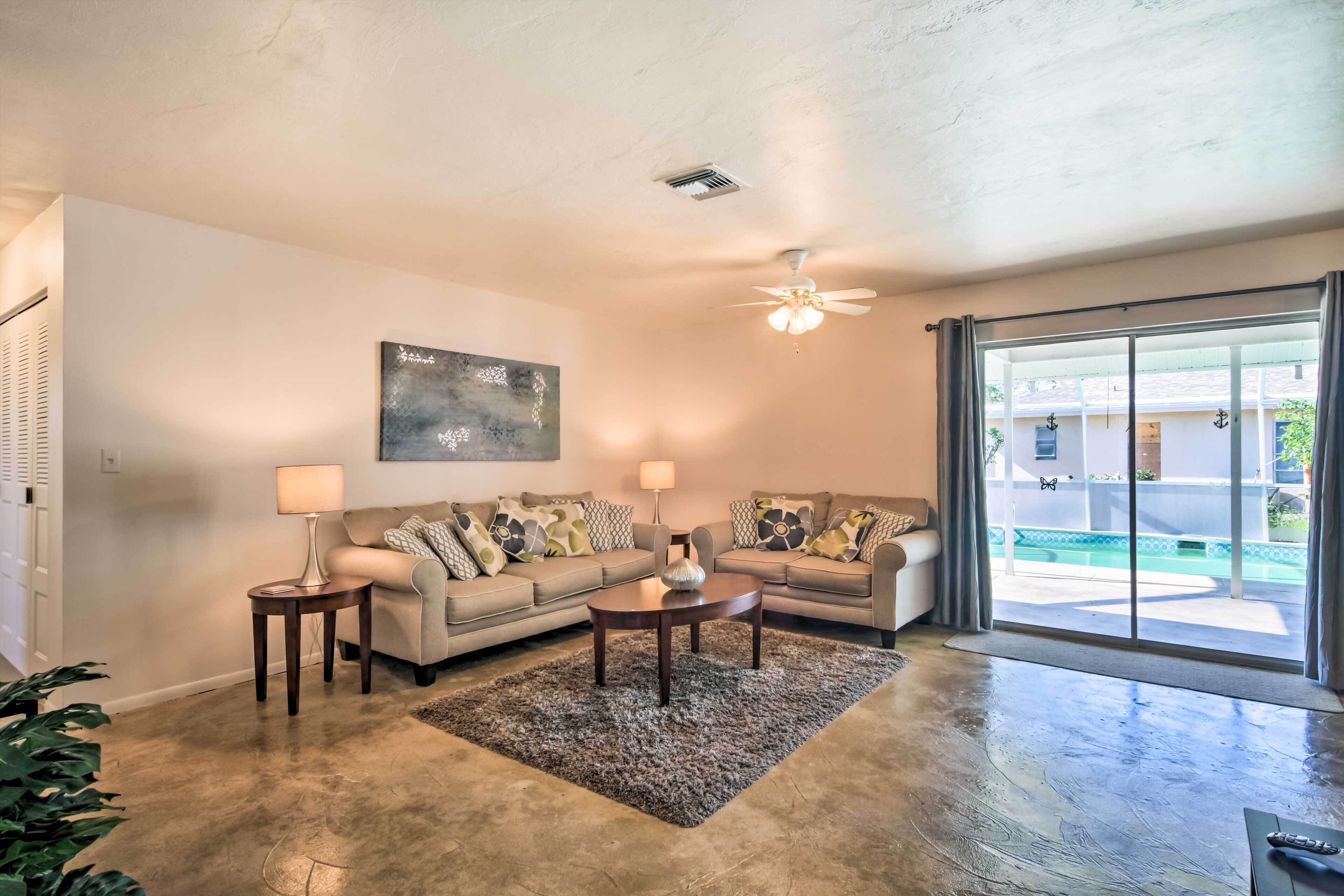A living room with a sofa set, two side tables, a coffee table, and a ceiling fan.