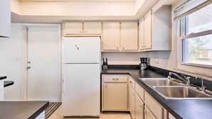 Eine moderne Küche mit weißen Schränken, einer Edelstahlspüle und einem Kühlschrank.