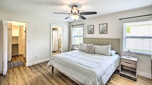 A bedroom with a bed, a nightstand, a ceiling fan, a window with blinds, and a walk-in closet.
