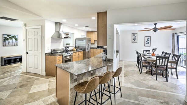 A modern kitchen with a central island, bar stools, and a dining area with a large table and chairs.
