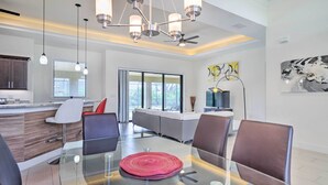 A modern kitchen with dark cabinets, a white countertop, and a red chair. - Cape Coral Getaway w/ Private Outdoor Pool! (Cape Coral)