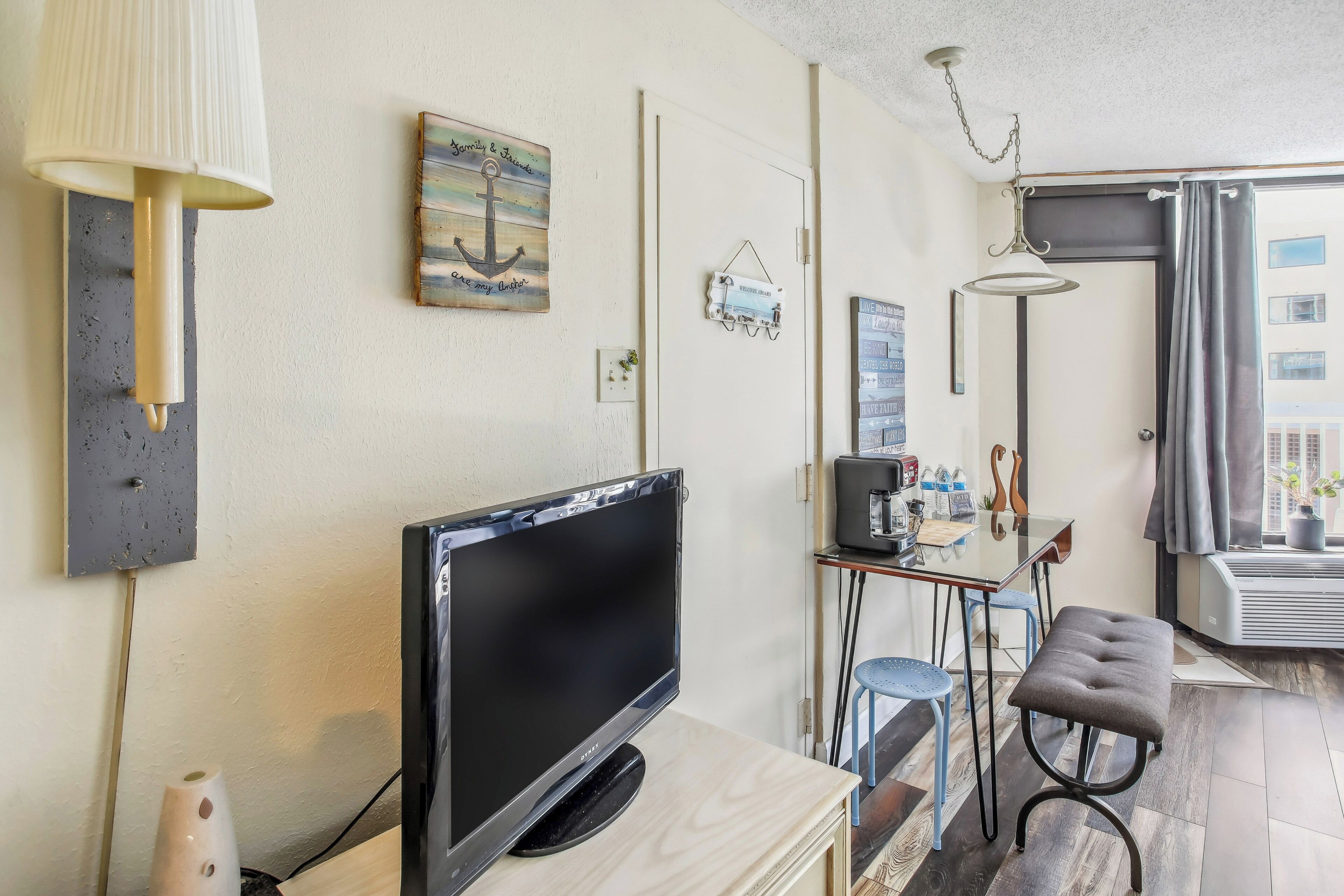 A modern living room with a flat-screen TV, a lamp, and a dining area with a table and chairs.