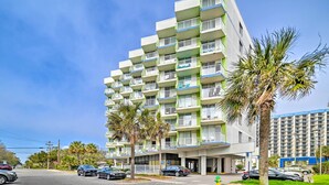 A multi-story hotel with balconies, a parking area, and palm trees. - Caravelle Tower Condo Rental: Walk to Beach (Myrtle Beach)