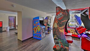 A row of arcade machines in a room with wooden flooring and a ceiling with a grid pattern. - Caravelle Tower Condo Rental: Walk to Beach (Myrtle Beach)
