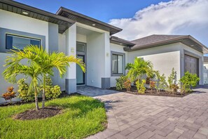 A modern two-story house with a paved driveway and a well-maintained lawn. - Cape Coral Home w/ Screened-in Lanai + Pool! (Cape Coral)