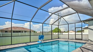 Una piscina techada con un aro de baloncesto, rodeada por una cerca y con vistas a casas al fondo.