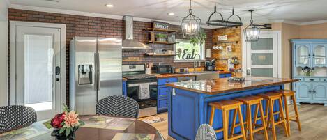 Une cuisine moderne dotée d’un îlot central, de tabourets de bar et d’un coin repas avec une table ronde.