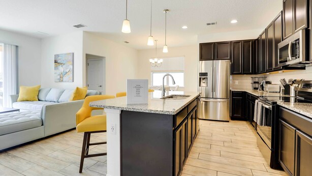 A modern kitchen with dark cabinets, stainless steel appliances, and a central island. - 12 Mi to Disney: Home w/ Pool Access + Grill (Davenport)