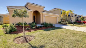 A residential house with a front entrance, a driveway, and a small garden with various plants. - 12 Mi to Disney: Home w/ Pool Access + Grill (Davenport)