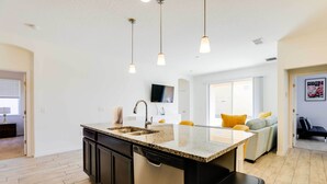 A modern kitchen with a central island, built-in dishwasher, and pendant lighting. - 12 Mi to Disney: Home w/ Pool Access + Grill (Davenport)