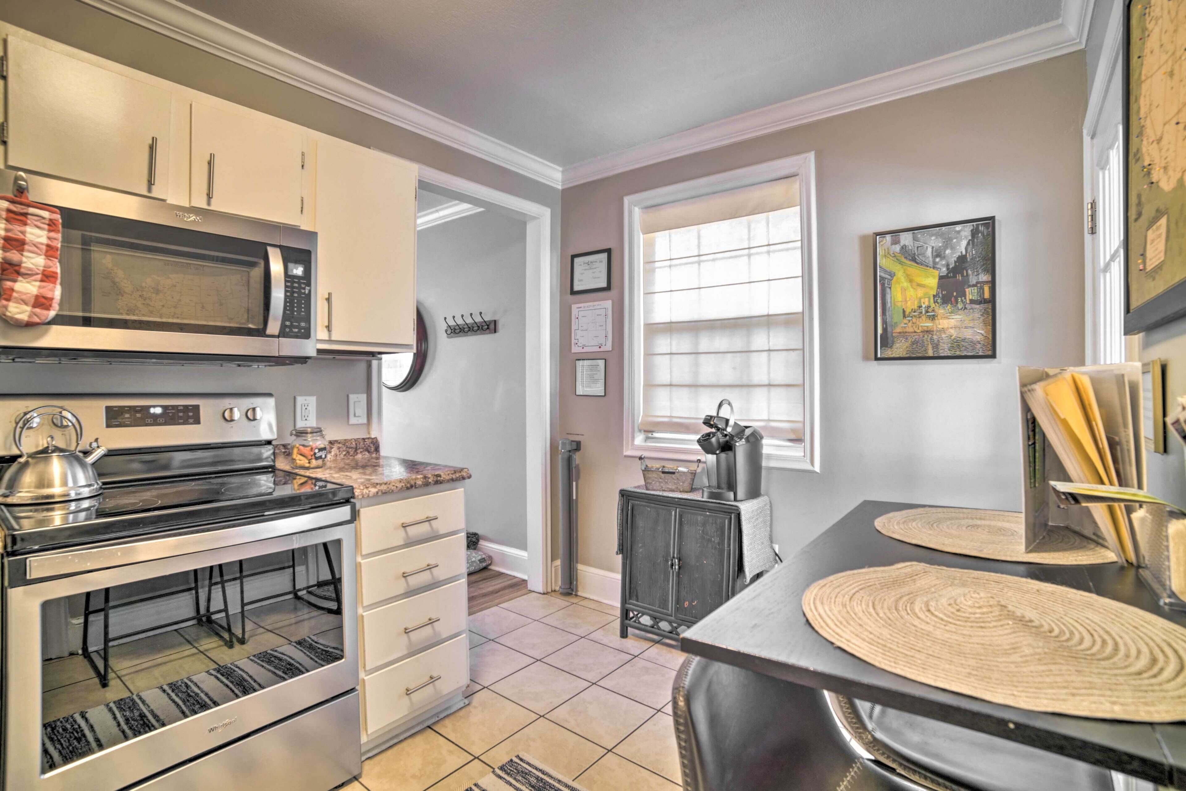 A kitchen with a microwave, stove, oven, and a dining area with a table and chairs.