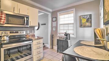 A kitchen with a microwave, stove, oven, and a dining area with a table and chairs.