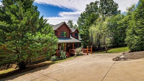 A log cabin with a porch, surrounded by trees. - Lake Hartwell Cabin, Perfect for Clemson Game Day (Fair Play)