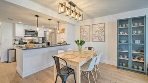 Eine moderne Küche mit weißen Schränken, einer zentralen Kochinsel und einem Essbereich mit Holztisch und Stühlen.