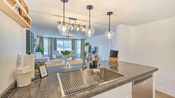 Eine moderne Küche mit Granit Arbeitsplatte, Edelstahl-Spüle und Pendelleuchten.