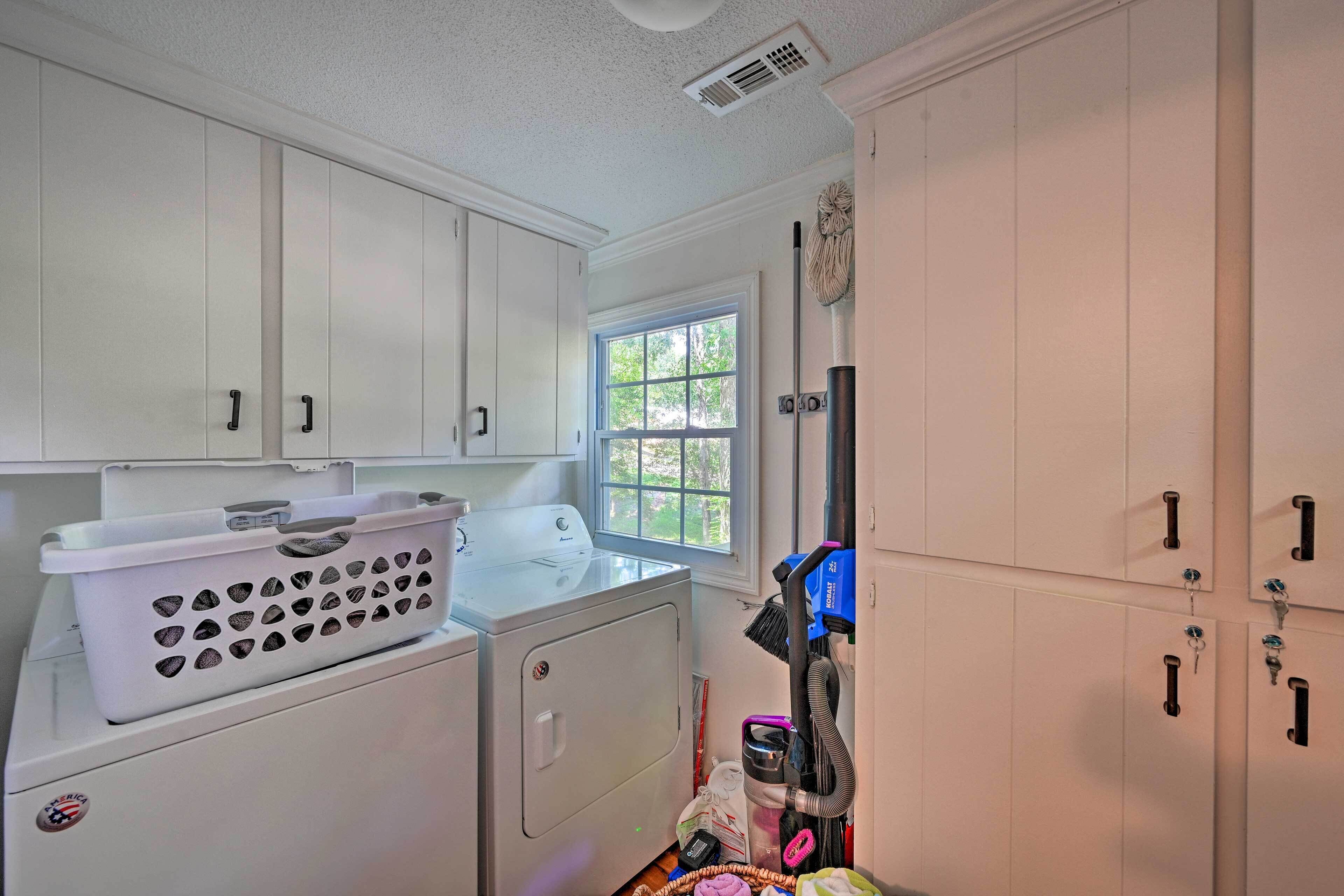 A laundry room with a washer and dryer, a window, and a vacuum cleaner.