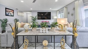 Una sala de estar moderna con un sofá gris, una mesa de centro de mármol y elementos decorativos como jarrones y esculturas.