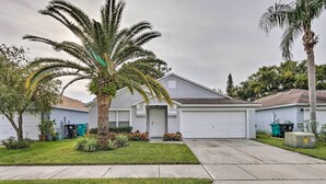 Una casa con jardín delantero, una palmera y un garaje.