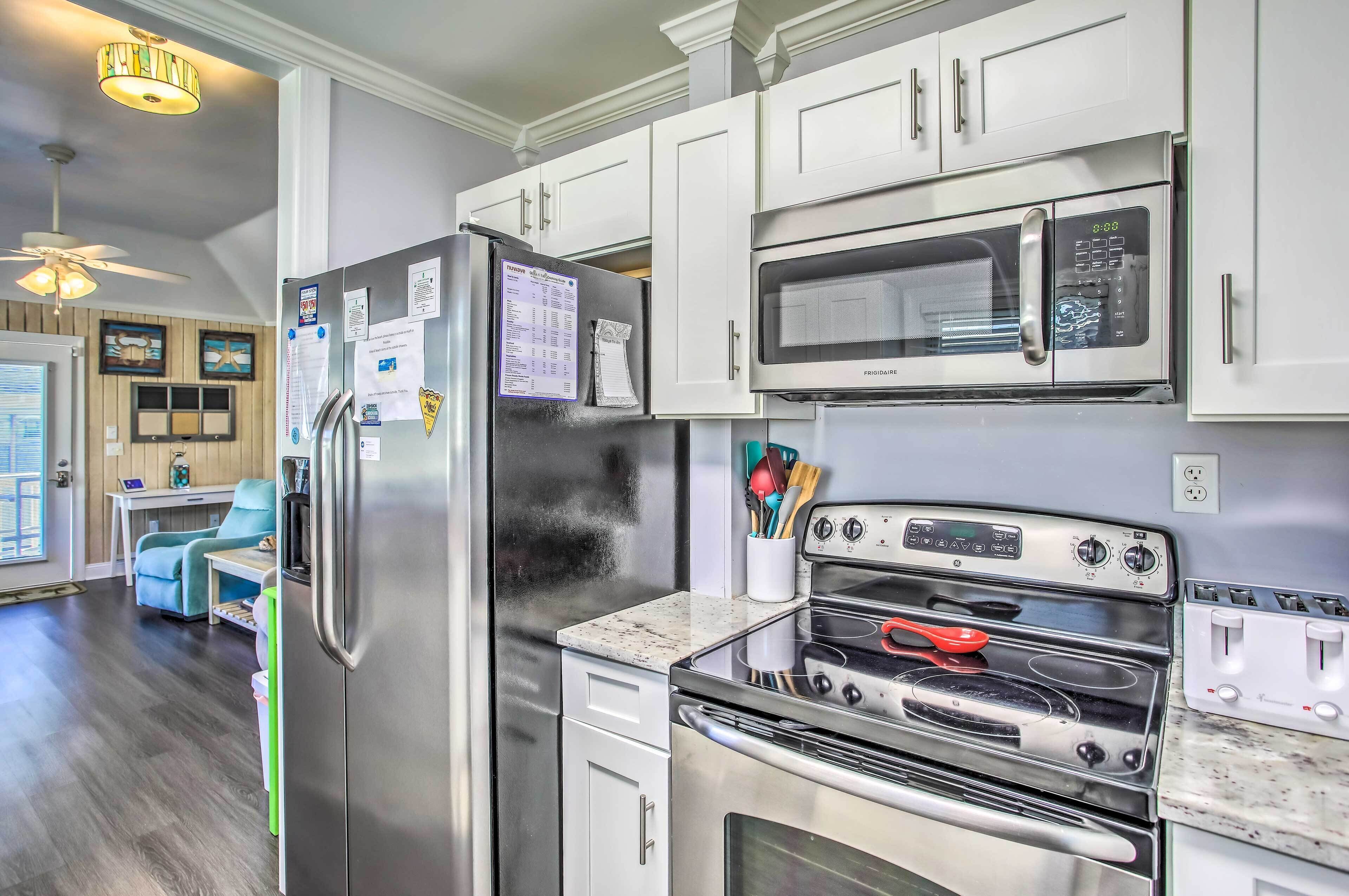 A modern kitchen with stainless steel appliances, white cabinetry, and a dining area with a blue chair.