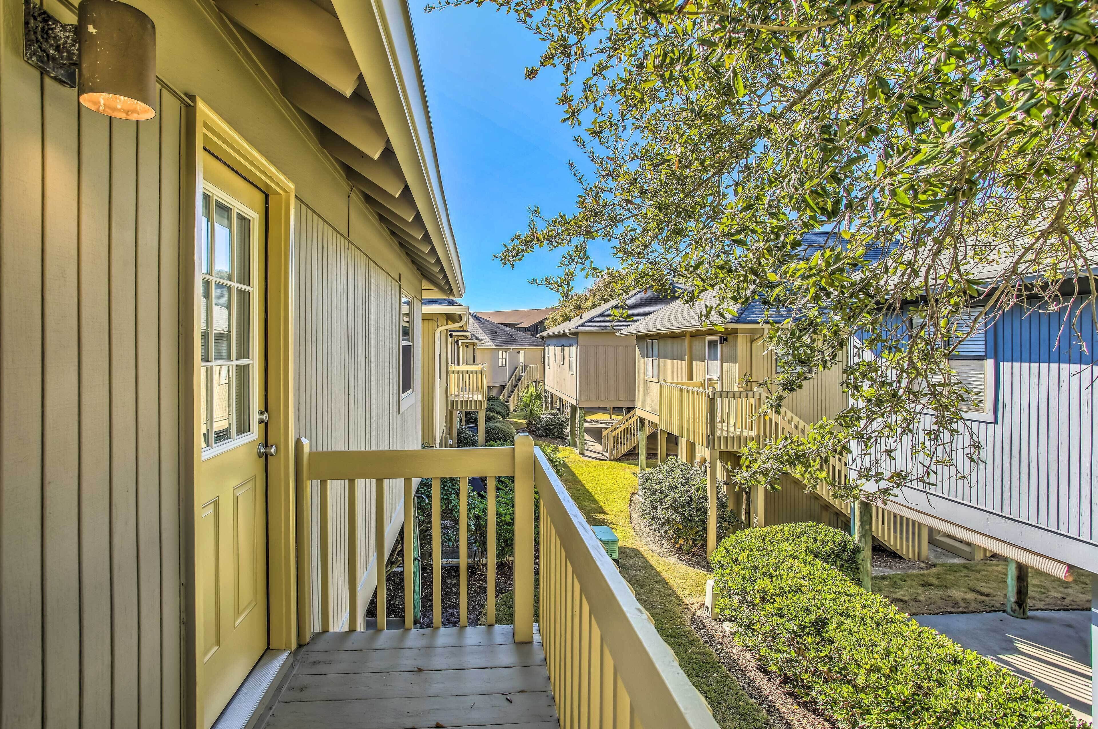 A residential building with a yellow exterior, a wooden staircase, and a small garden area.