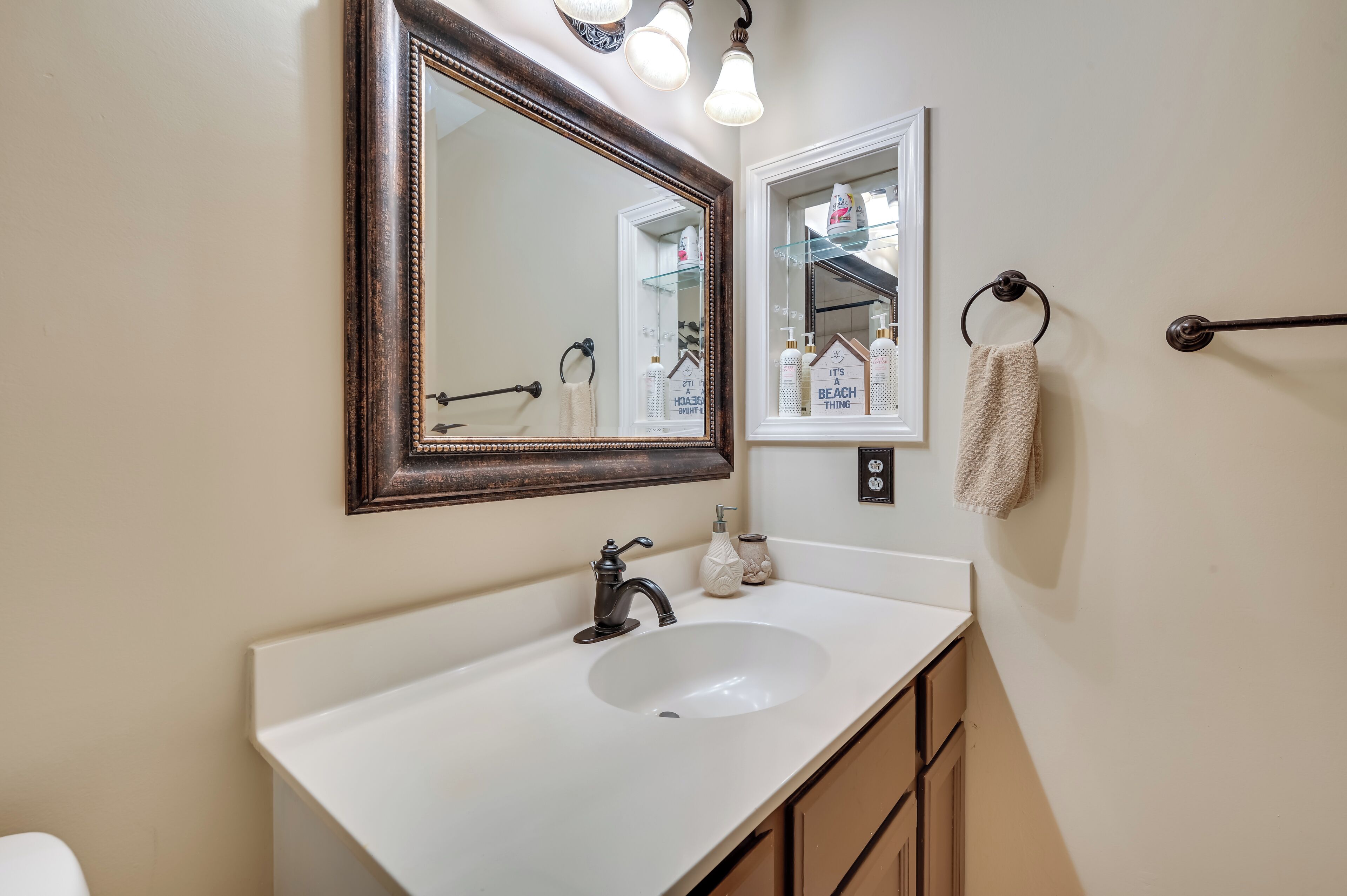 A bathroom with a white sink, a large mirror, and a towel rack.